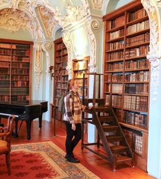 Dame staat aan laddertje in historische bibliotheek