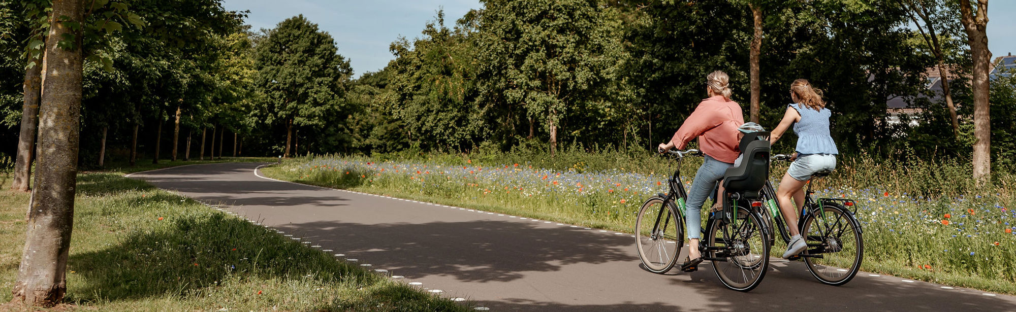 Twee dames fietsen naast elkaar tussen het groen over de Parkstadroute. 