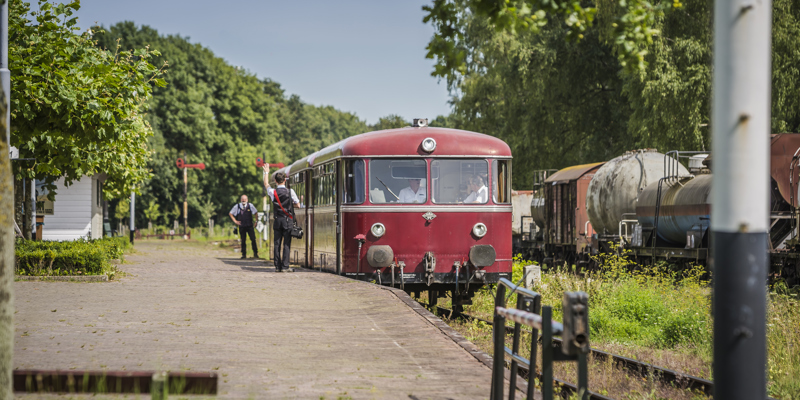 Railbus van de Miljoenenlijn naast het perron met conducteurs