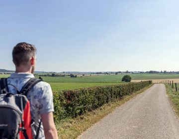 Wandelaar met rugzak over een geasfalteerd pad bij Simpelveld