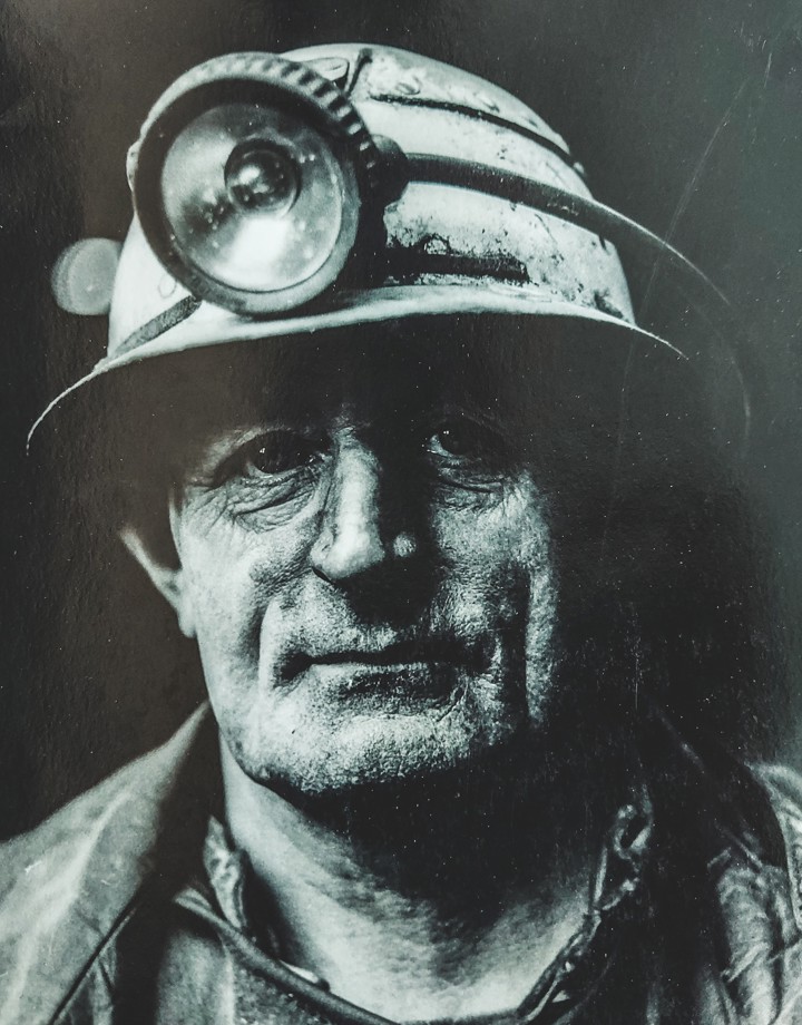 Zwart wit foto van Mijnwerker met helm en hoofdlamp op.