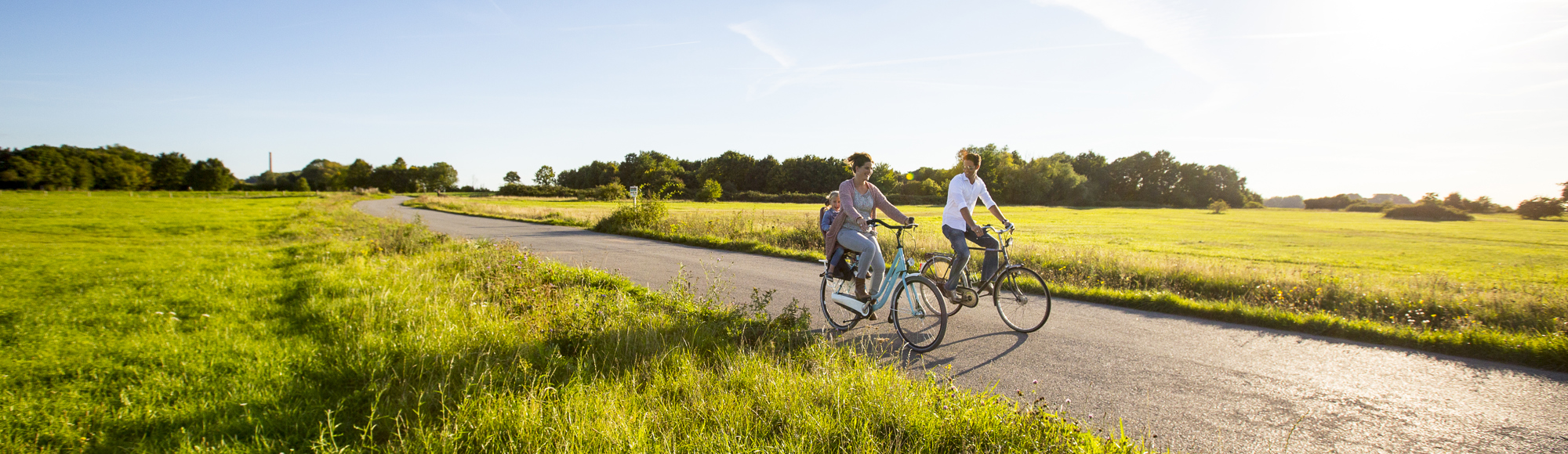 Moeder met kind achterop en vader fietsen door Zuid-Limburg