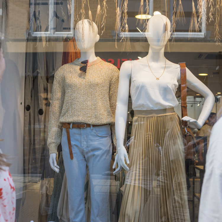 Twee vrouwen kijken in de etalage naar kleding
