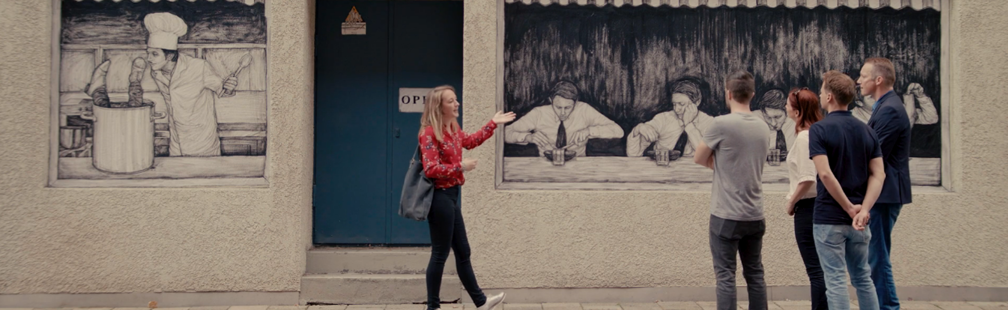 Een jonge vrouw geeft een rondleiding aan een groepje mensen over street art in Heerlen