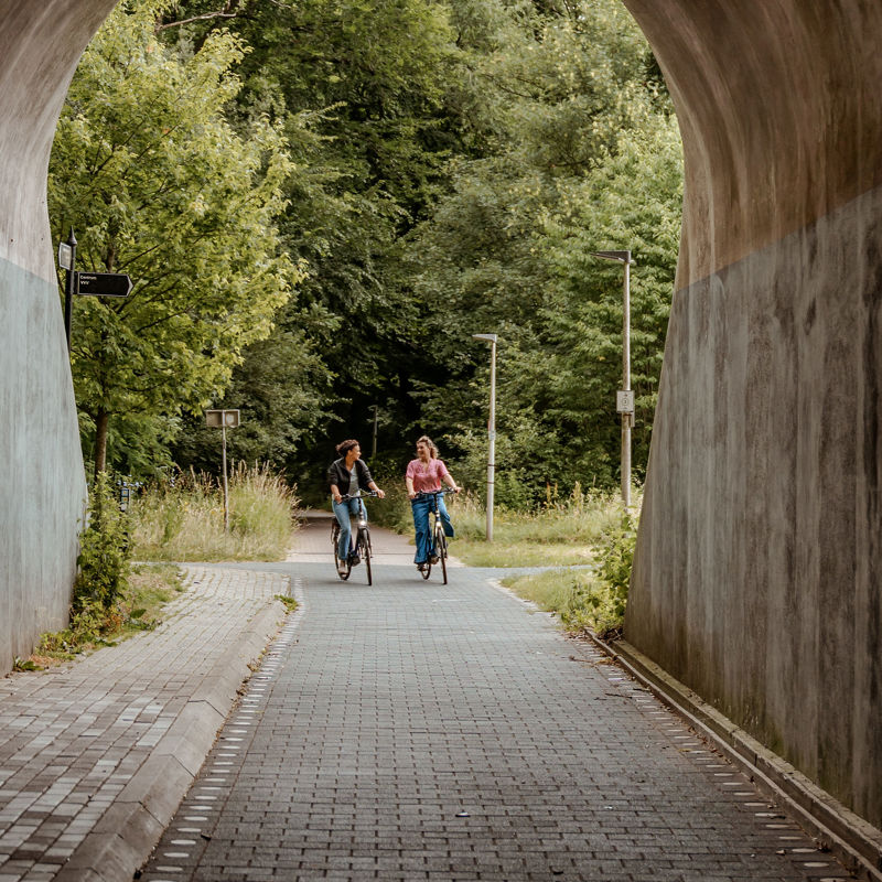 Twee dames fietsen naast elkaar een tunnel in op de Parkstadroute in Kerkrade.