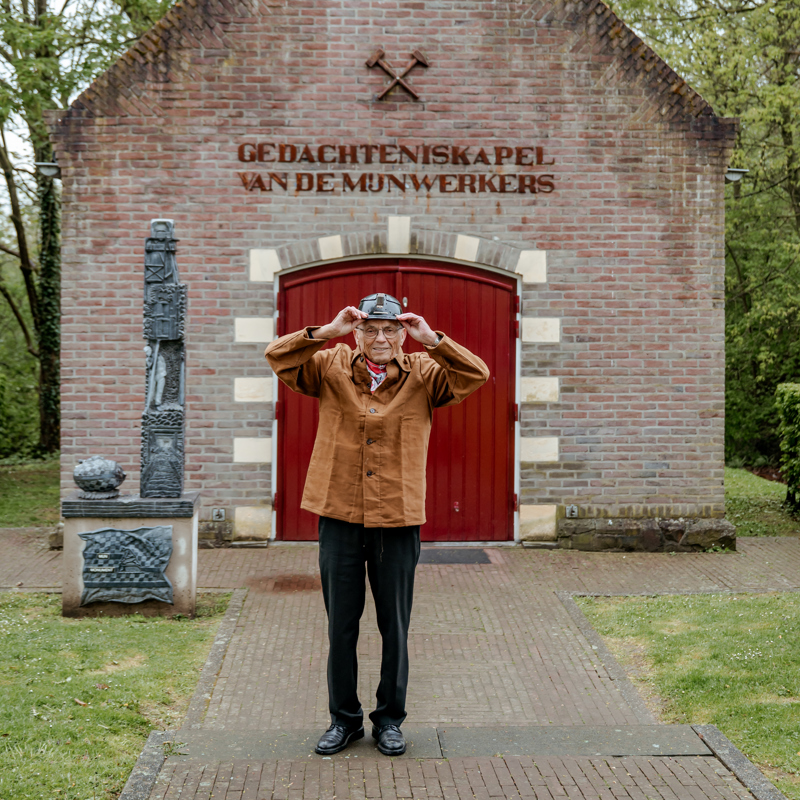 Oud-mijnwerker houdt zijn helm vast voor de gedachteniskapel van de mijnwerkers in landgraaf.