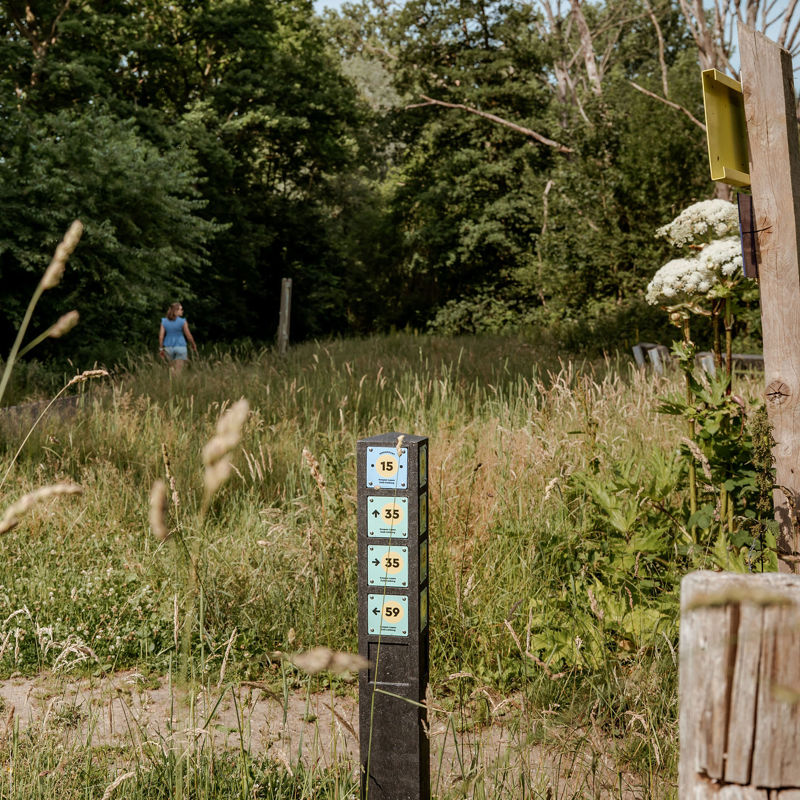 Knooppuntenpaal langs de Parkstadroute met een wandelaar op de achtergrond.