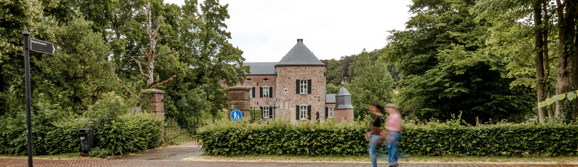 Twee wandelaars op het voetpad voor Kasteel Erenstein, met het kasteel op de achtergrond.