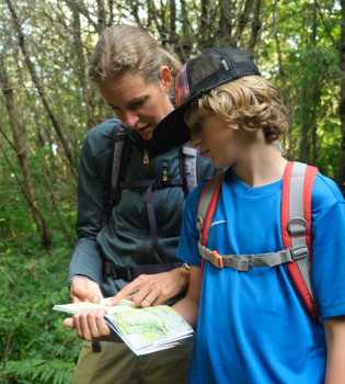 Moeder en zoon in het bos de route aan het bestuderen in een wandelboekje 